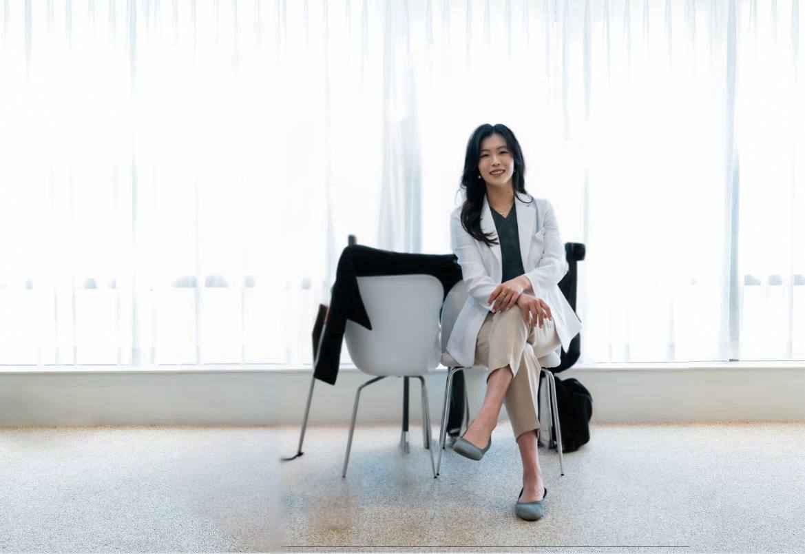 A female dermatologist sitting in the hospital lobby, smiling brightly and warmly greeting you. 여자 미용의사가 병원 로비에 앉아서 환하게 당신을 반기고 웃고 있다